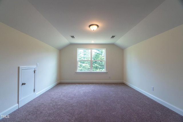 additional living space featuring baseboards, visible vents, and vaulted ceiling