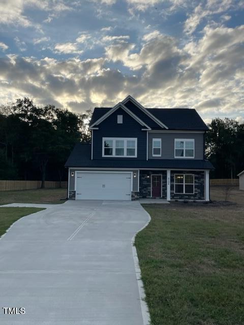 view of front of home with a front yard, concrete driveway, fence, a garage, and a porch