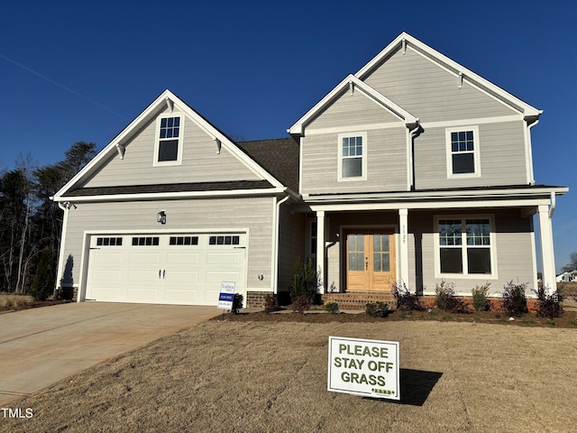 view of front of house featuring french doors, a garage, a porch, and concrete driveway