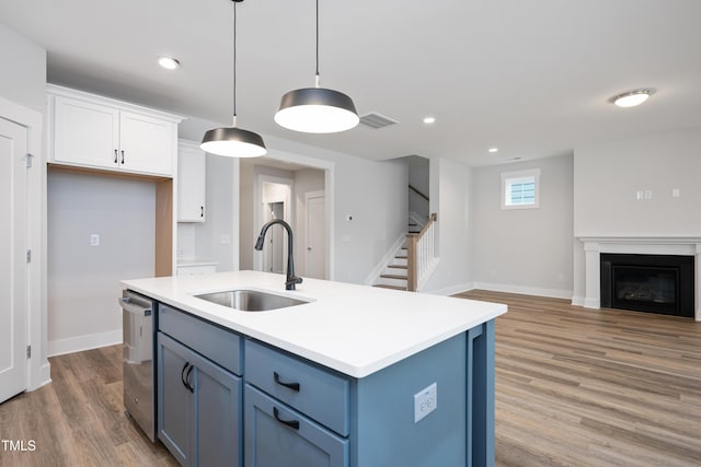 kitchen featuring sink, a center island with sink, hanging light fixtures, stainless steel dishwasher, and white cabinets