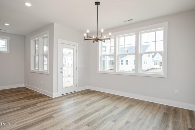 unfurnished dining area featuring wood-type flooring and a chandelier