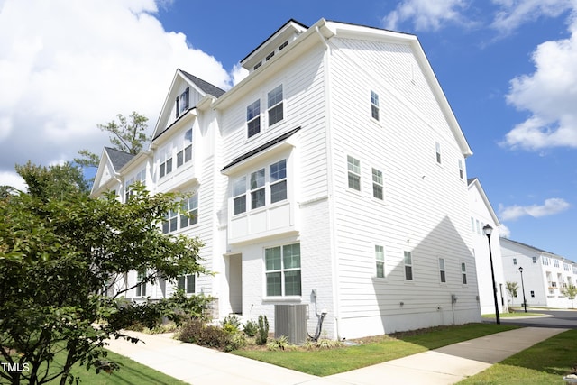 view of side of property featuring a yard and central air condition unit