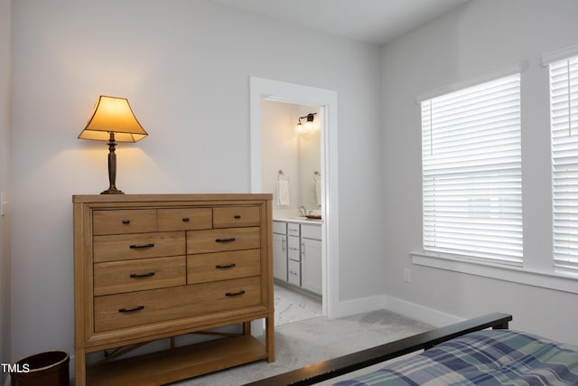 bedroom with light carpet, ensuite bath, multiple windows, and sink