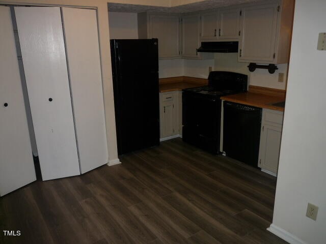 kitchen with range hood, black appliances, and dark wood-type flooring