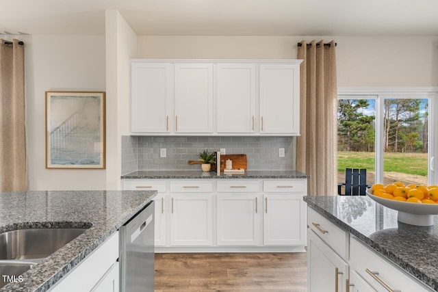 kitchen with light hardwood / wood-style flooring, dark stone counters, and white cabinetry