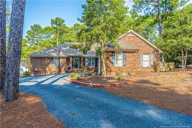 ranch-style house with crawl space, roof with shingles, aphalt driveway, and brick siding