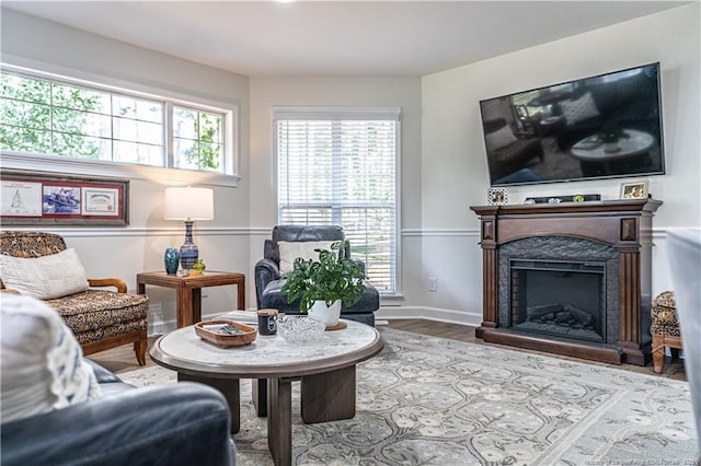 living area featuring baseboards, a fireplace with raised hearth, and wood finished floors