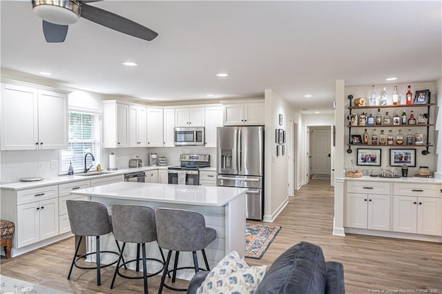 kitchen featuring a breakfast bar area, stainless steel appliances, light countertops, white cabinets, and a sink