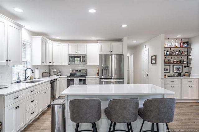 kitchen with appliances with stainless steel finishes, a center island, light countertops, and white cabinetry