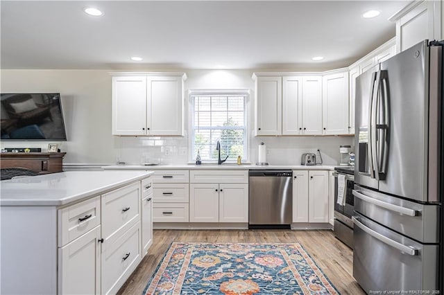 kitchen featuring light countertops, light wood-style flooring, appliances with stainless steel finishes, white cabinets, and a sink