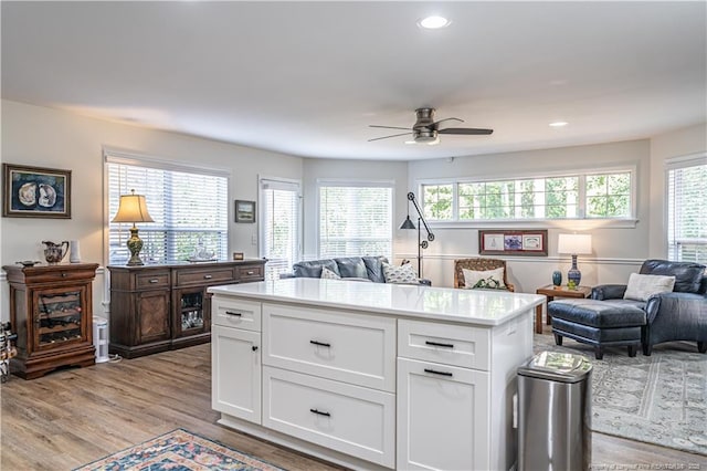 kitchen with open floor plan, light countertops, light wood finished floors, and white cabinets