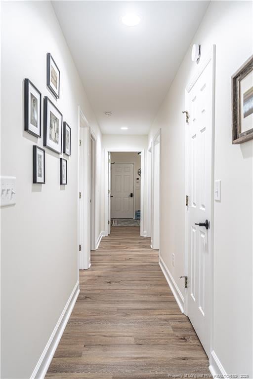 hallway featuring wood finished floors and baseboards