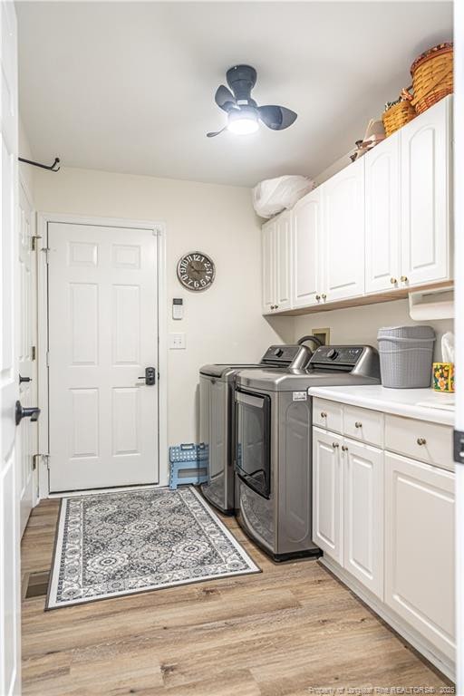 clothes washing area featuring ceiling fan, light wood-style flooring, washer and clothes dryer, and cabinet space