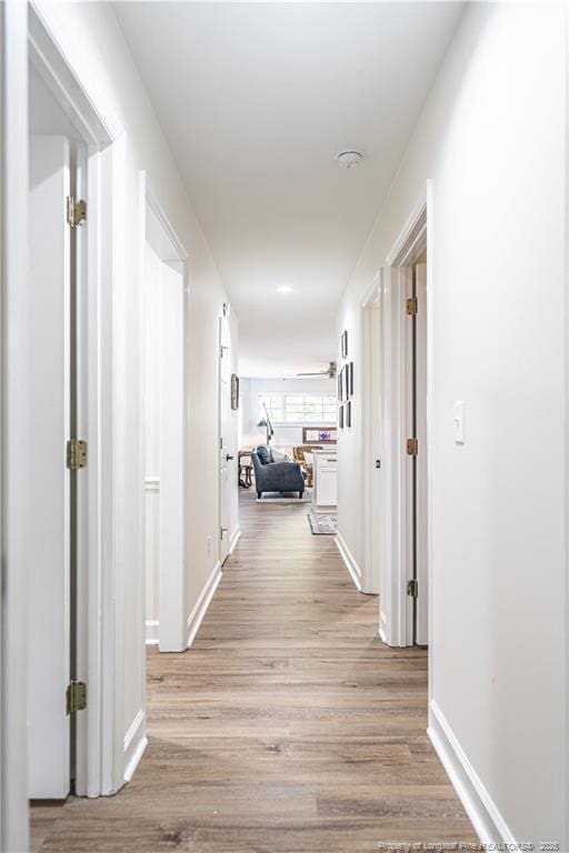 hall with light wood-style floors and baseboards