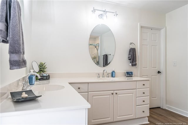 full bathroom with wood finished floors, a sink, baseboards, and double vanity