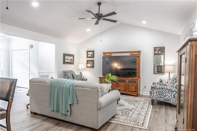 living room with a ceiling fan, vaulted ceiling, and light wood-style flooring