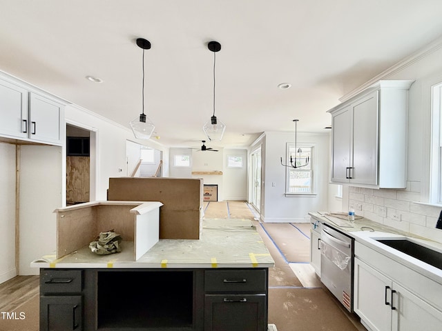 kitchen featuring dishwasher, a kitchen island, backsplash, pendant lighting, and a sink