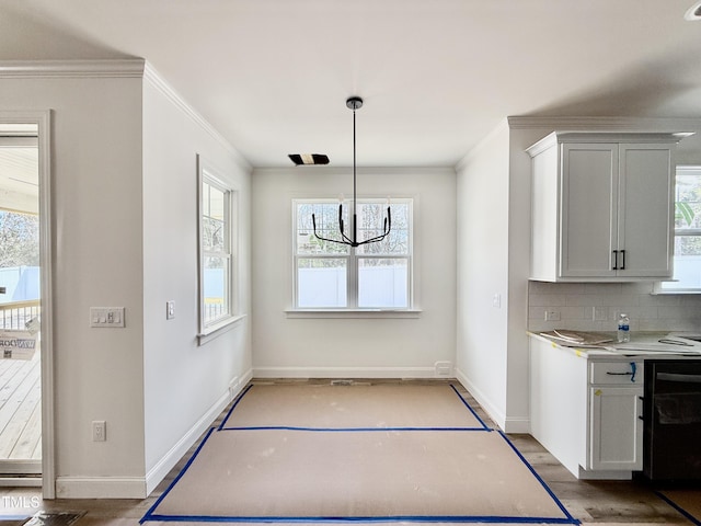 unfurnished dining area featuring light wood finished floors, ornamental molding, and a healthy amount of sunlight