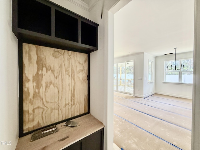 mudroom with a healthy amount of sunlight, crown molding, baseboards, and an inviting chandelier