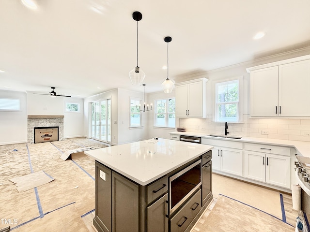 kitchen with a fireplace, white cabinets, tasteful backsplash, a sink, and appliances with stainless steel finishes