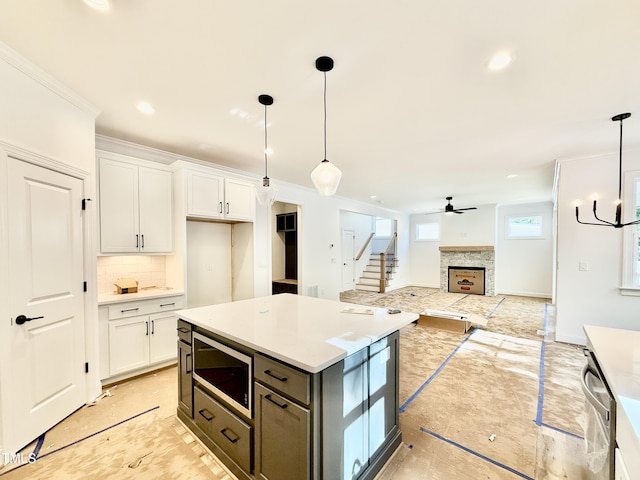 kitchen with crown molding, white cabinetry, a stone fireplace, and stainless steel appliances