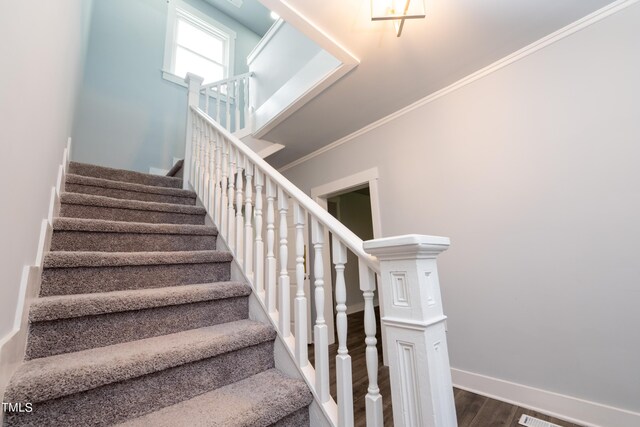 staircase with crown molding, baseboards, and wood finished floors