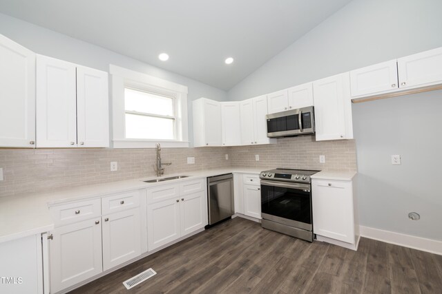 kitchen featuring a sink, vaulted ceiling, light countertops, appliances with stainless steel finishes, and white cabinetry