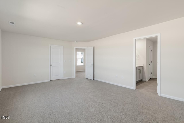 unfurnished bedroom featuring light colored carpet and ensuite bathroom