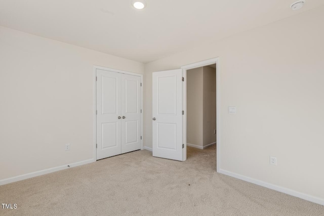 unfurnished bedroom featuring light carpet and a closet