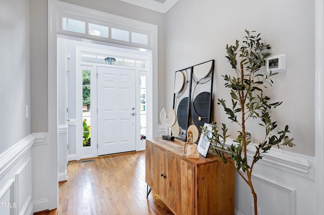 foyer entrance with light hardwood / wood-style flooring and ornamental molding