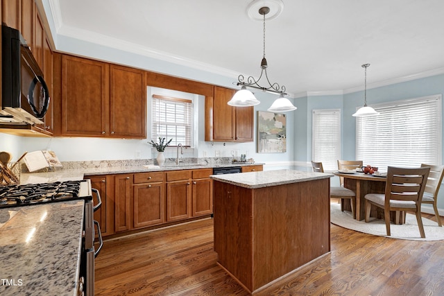 kitchen featuring gas stove, dark hardwood / wood-style flooring, hanging light fixtures, light stone countertops, and a kitchen island