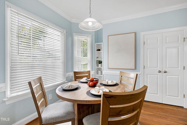 dining space with ornamental molding and light hardwood / wood-style flooring