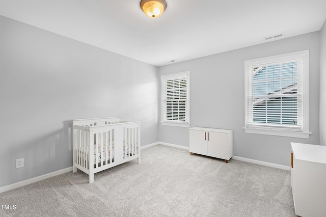 unfurnished bedroom featuring light carpet, a nursery area, and multiple windows