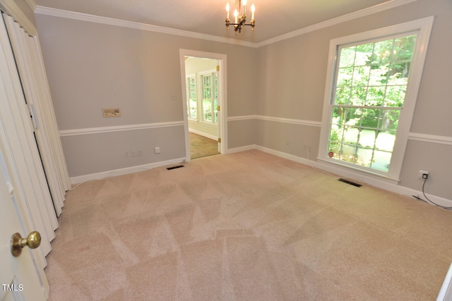 spare room featuring light colored carpet, a chandelier, and crown molding