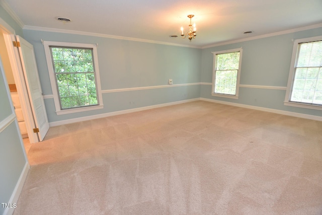 carpeted spare room featuring plenty of natural light, a notable chandelier, and ornamental molding