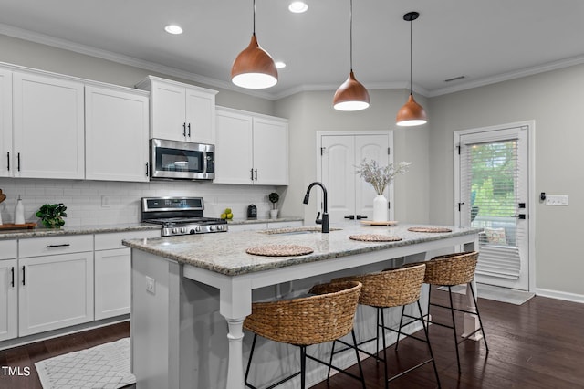 kitchen featuring stainless steel appliances, white cabinetry, a kitchen island with sink, and sink