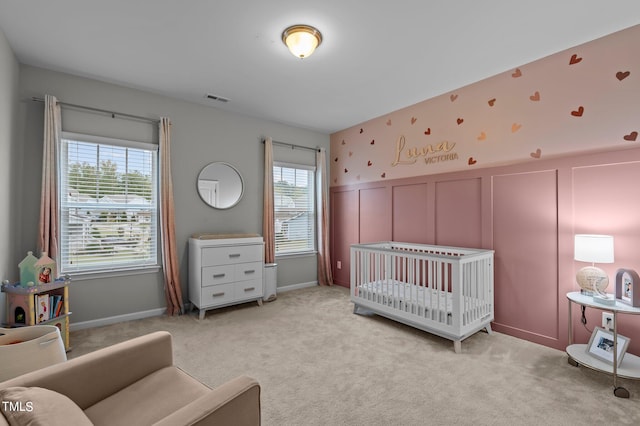 bedroom featuring a crib and light colored carpet