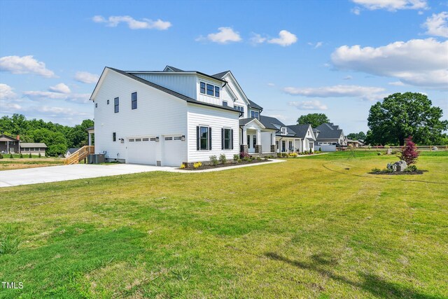 view of front facade featuring a front yard, a garage, and central AC unit