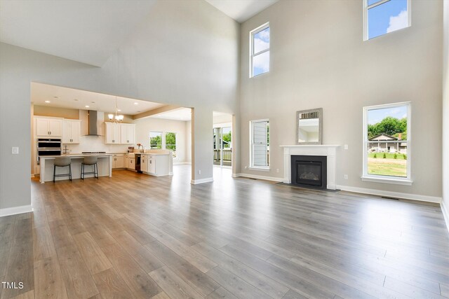 unfurnished living room with light wood-type flooring, a high ceiling, and a wealth of natural light