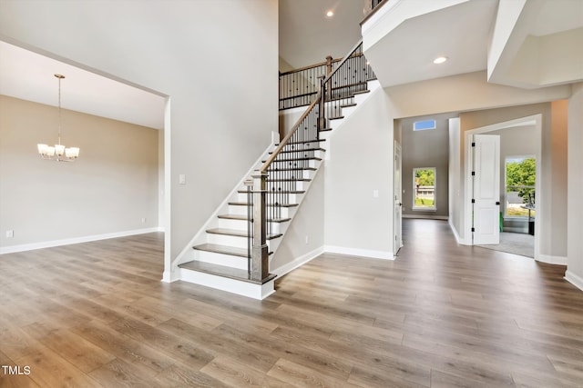 stairway with a high ceiling, hardwood / wood-style floors, and a notable chandelier