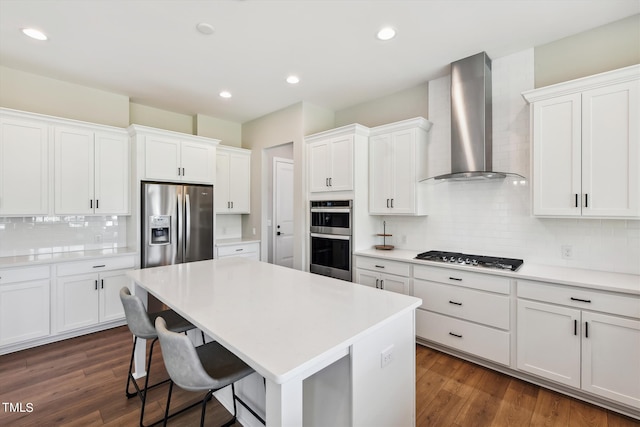 kitchen with appliances with stainless steel finishes, wall chimney exhaust hood, white cabinetry, and dark hardwood / wood-style flooring