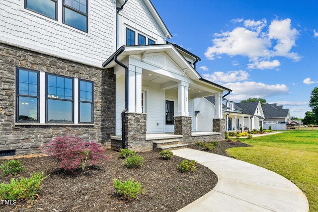 entrance to property featuring covered porch and a yard