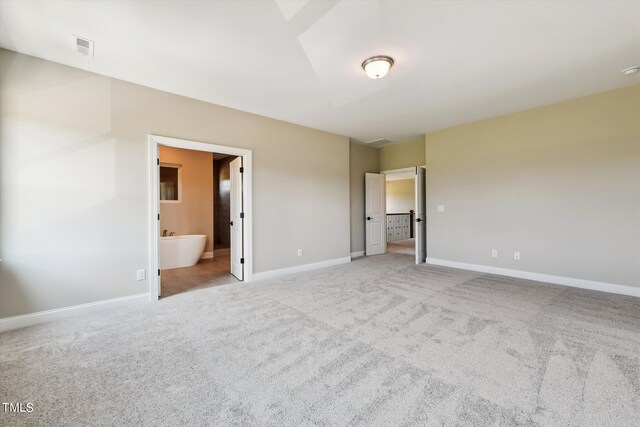 unfurnished bedroom with connected bathroom and light colored carpet