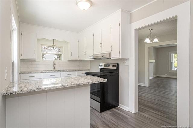 111 Sanford Rd, Laurinburg, NC 28352 - kitchen with a sink, stainless steel electric range, under cabinet range hood, an inviting chandelier, and white cabinetry