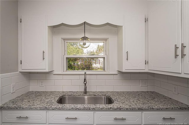 111 Sanford Rd, Laurinburg, NC 28352 - kitchen with backsplash, white cabinetry, light stone counters, and a sink