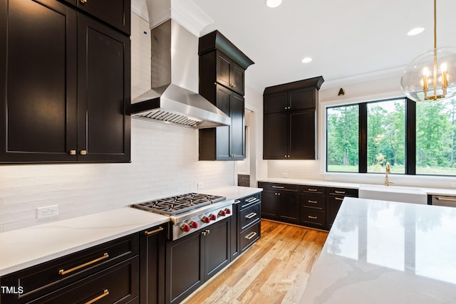 kitchen featuring wall chimney exhaust hood, sink, stainless steel gas cooktop, light hardwood / wood-style flooring, and backsplash