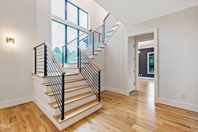 stairway with hardwood / wood-style flooring, crown molding, and a healthy amount of sunlight