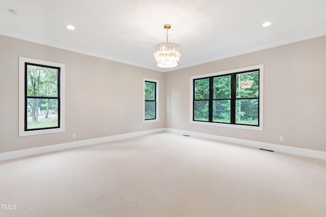 empty room with ornamental molding, a notable chandelier, and carpet floors