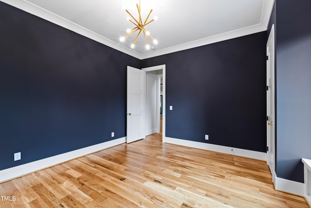 unfurnished room with an inviting chandelier, light wood-type flooring, and crown molding