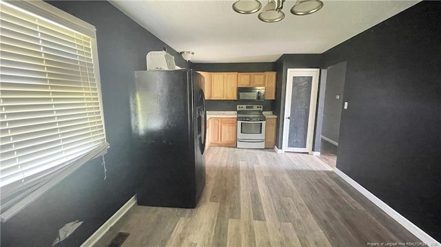 kitchen featuring light brown cabinets, black appliances, an inviting chandelier, light wood-style flooring, and baseboards